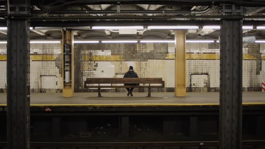 Woman sits on a bench at a train station