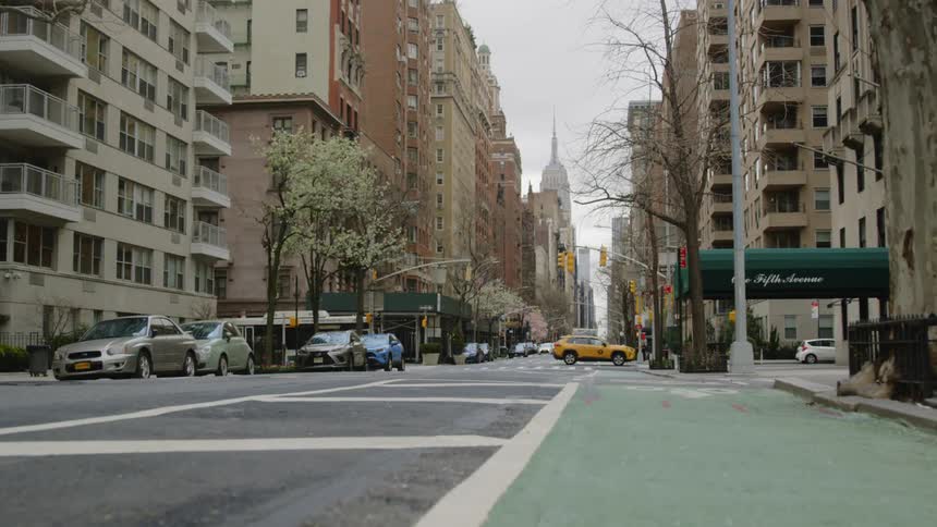 A taxi cab and a city bus cross through a city intersection on a city street