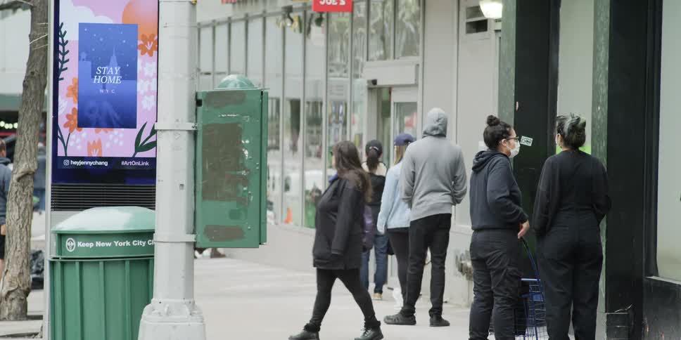 People line up outside a store and wait to be allowed in
