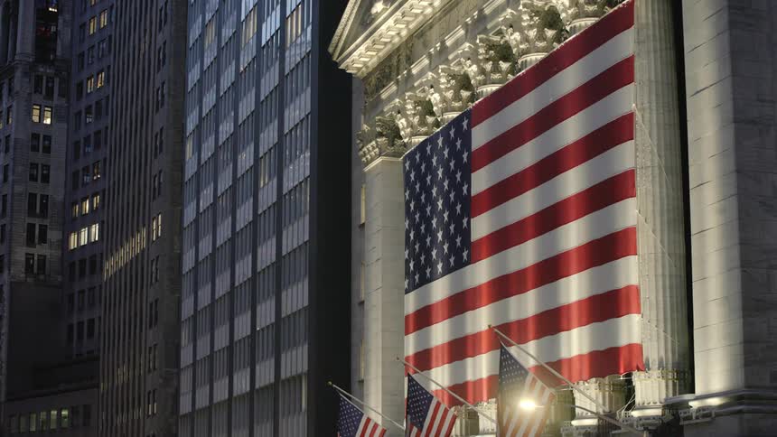 Light shines on the american flags in front of the new york stock exchange building