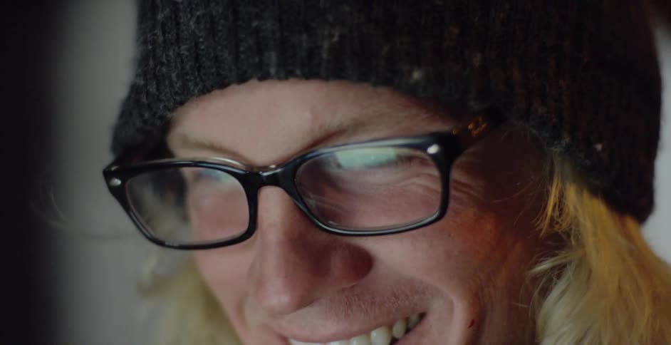 A young caucasian male scratches his face and smiles