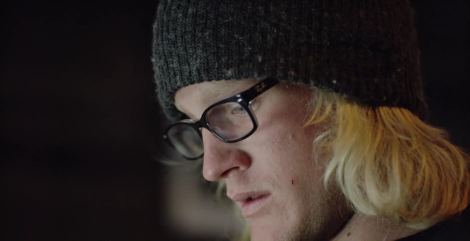 Man wearing eyeglasses and knit cap studies