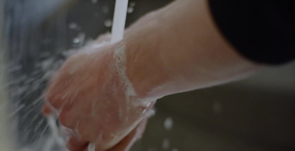 A person washes their hands in a sink