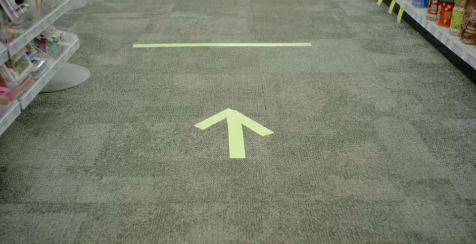 Tape creates lines and arrows on the floor of a grocery
