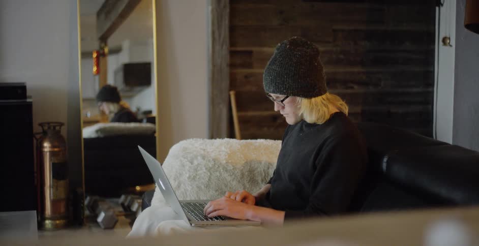 A man is typing on his keyboard on the couch