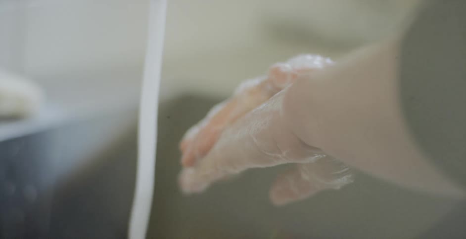 A person thoroughly washes their hands with soap and running water at the sink