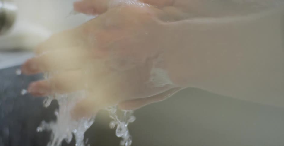 A person washes their hands and shuts the water off