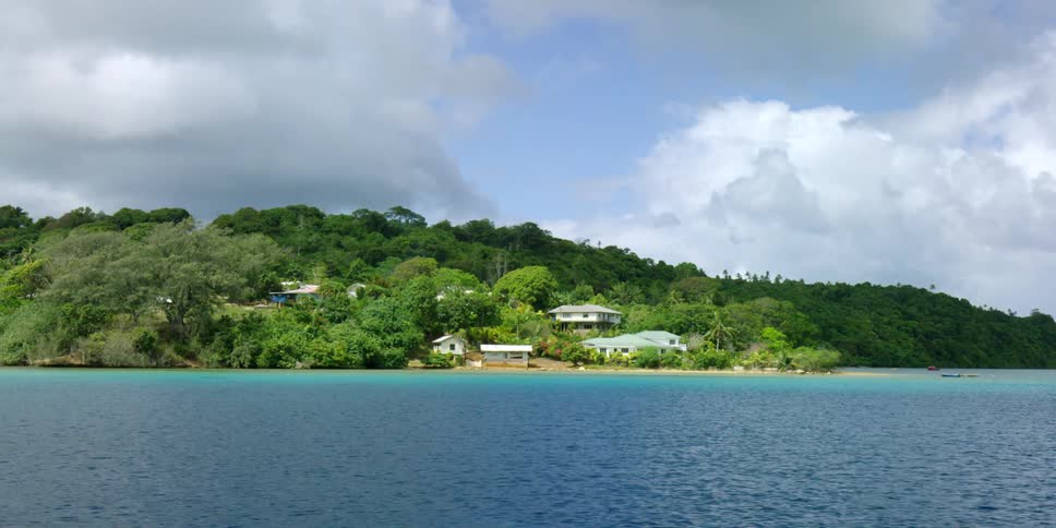 View of homes, hills, trees and the shoreline under a cloudy sky