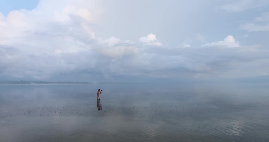 Person standing in shallow water taking photographs