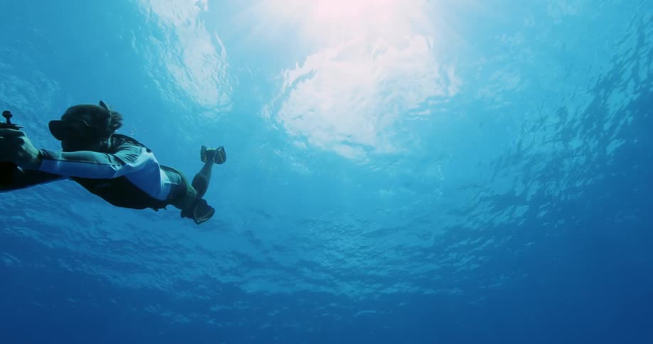 Diver swimming in the ocean with an underwater camera