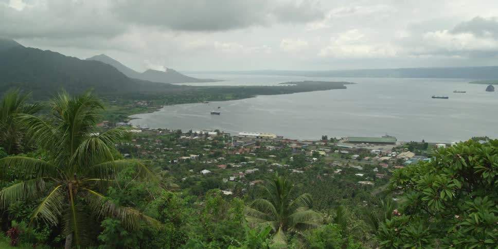 An ocean side city with mountains over it