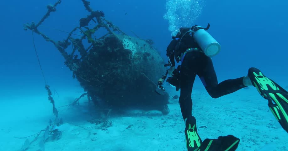 A scuba diver swims toward a sunken boat