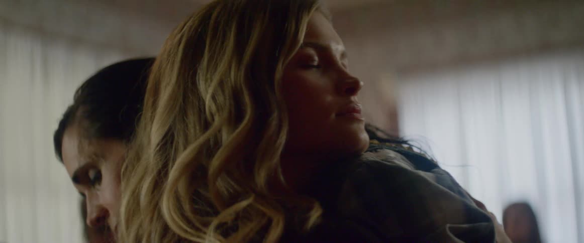 Two women hug in a room full of people