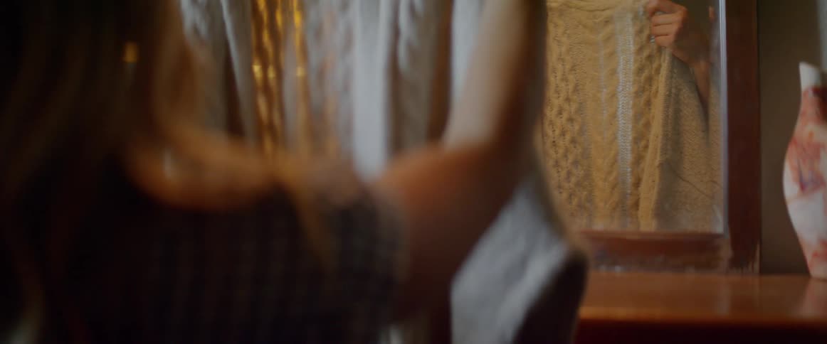 A woman unfolds a sweater and cries as she embraces it