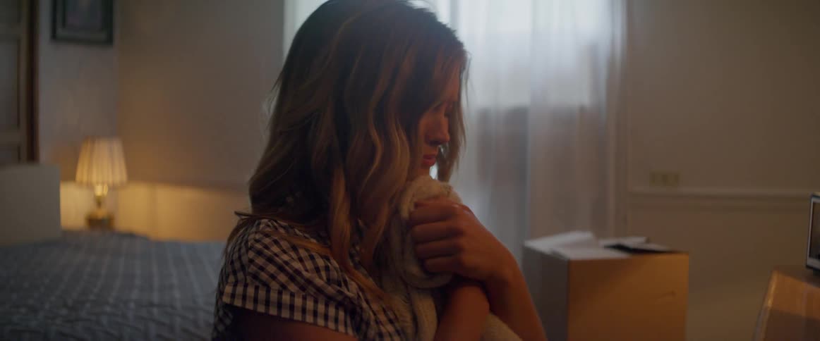A woman lifts a sweater and hugs it tight to her chest