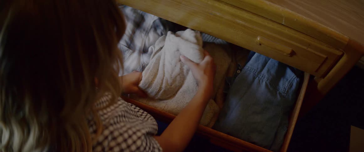 A woman pulls a sweater out of a dresser