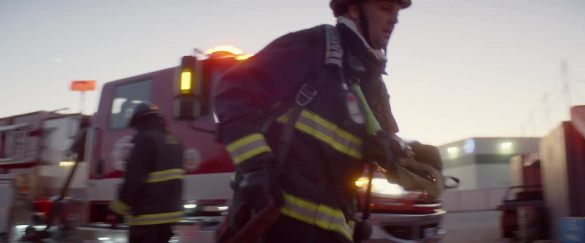 A firefighter running with a hose towards a fire