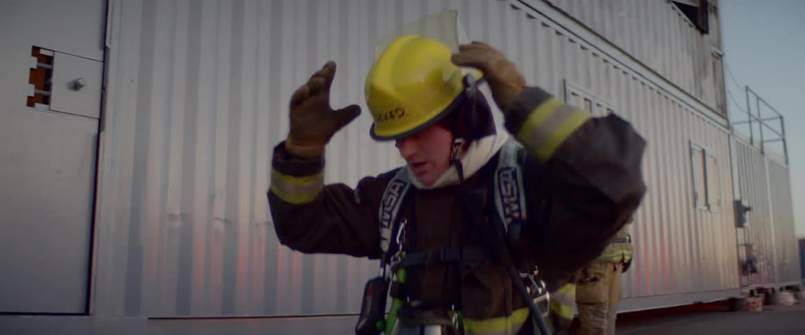 A firefighter raises his arms and yells at others while checking his equipment
