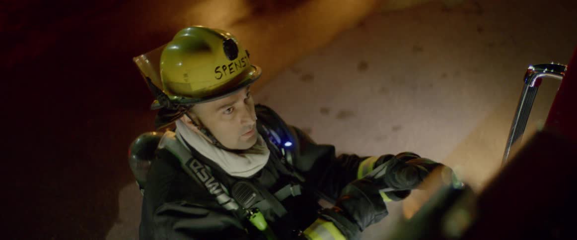 A firefighter standing outside of a fire engine putting on gloves