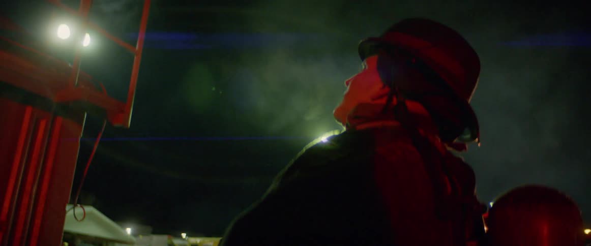 Fireman stands next to building looking up at balcony at night