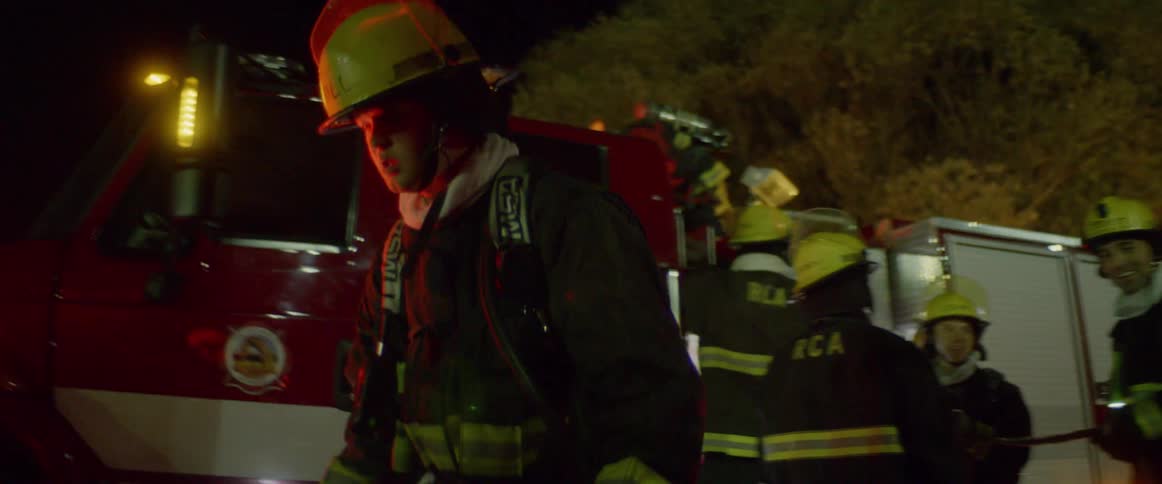 Firefighters walking and standing in front of a fire truck