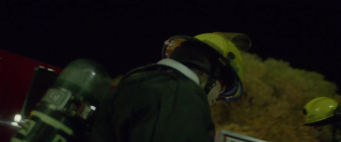 Firefighters stand outside a fire truck as they prepare to battle a fire
