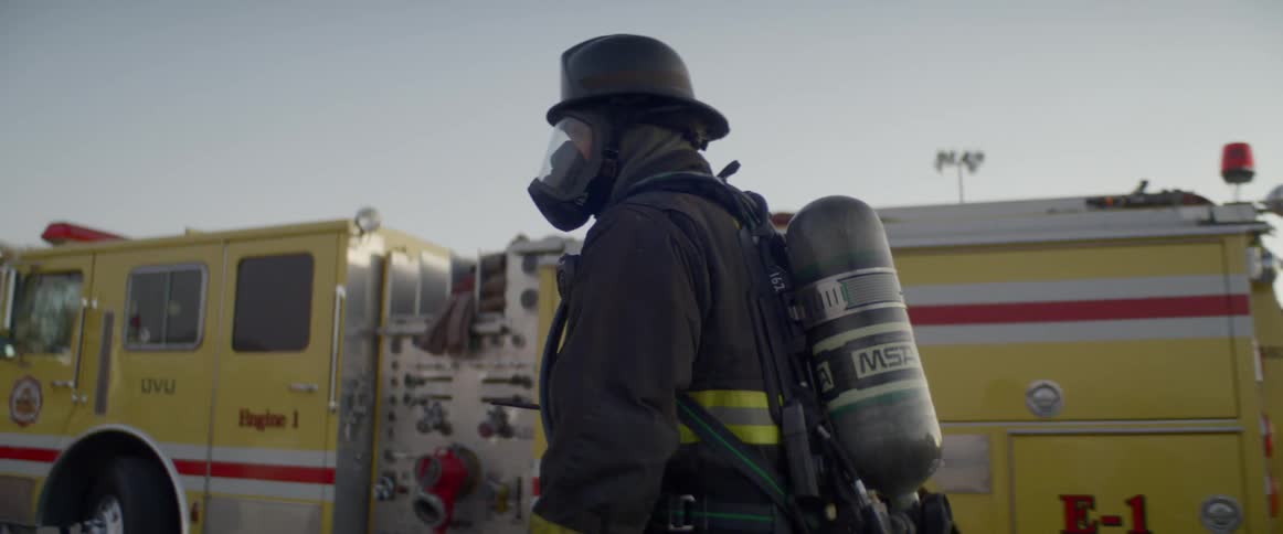 A firefighter walks past a truck to a group of other firefighters