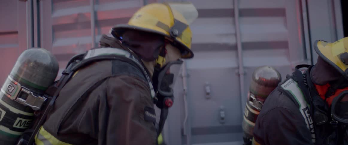 Firefighters in full gear stand outside the entrance to a building