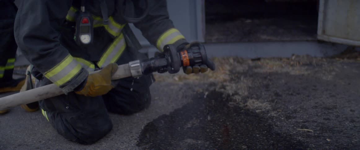 Water shoots out as a firefighter turns on a hose