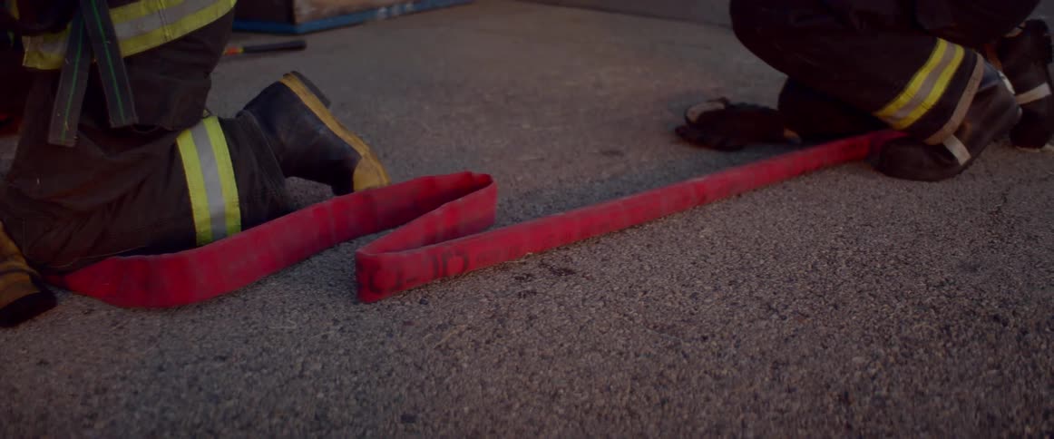 Firemen kneel on a firehose