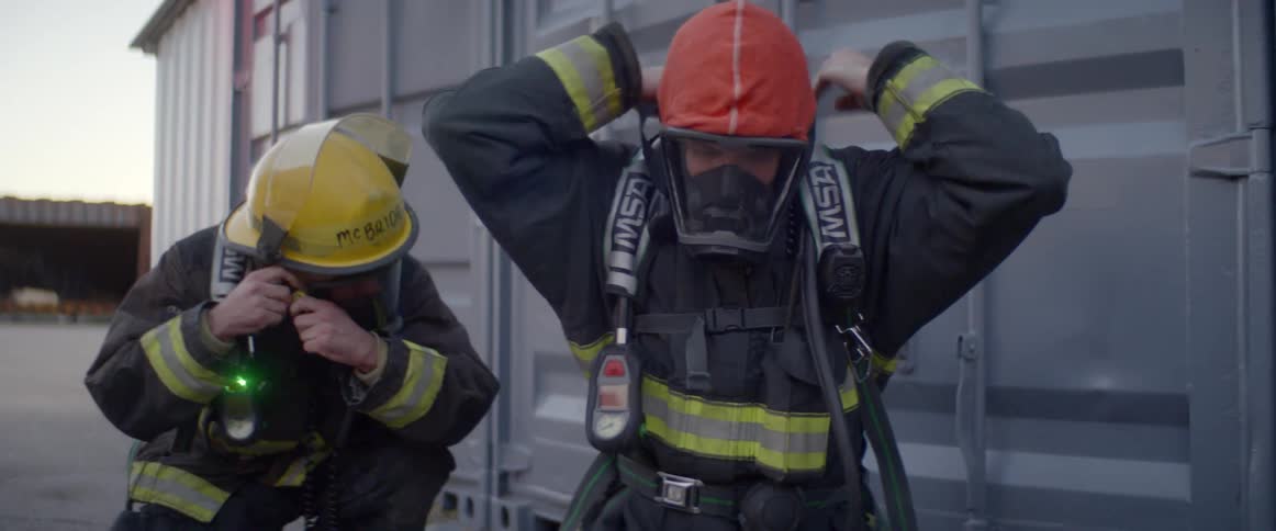 Firefighters outside of containers secure their oxygen masks and helmets