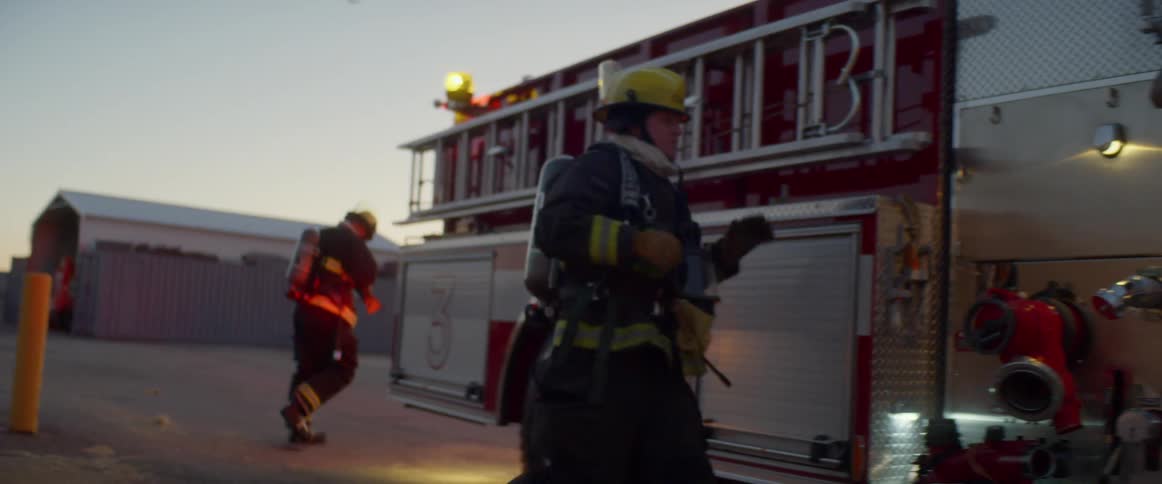 A firefighter runs and climbs on to a fire engine