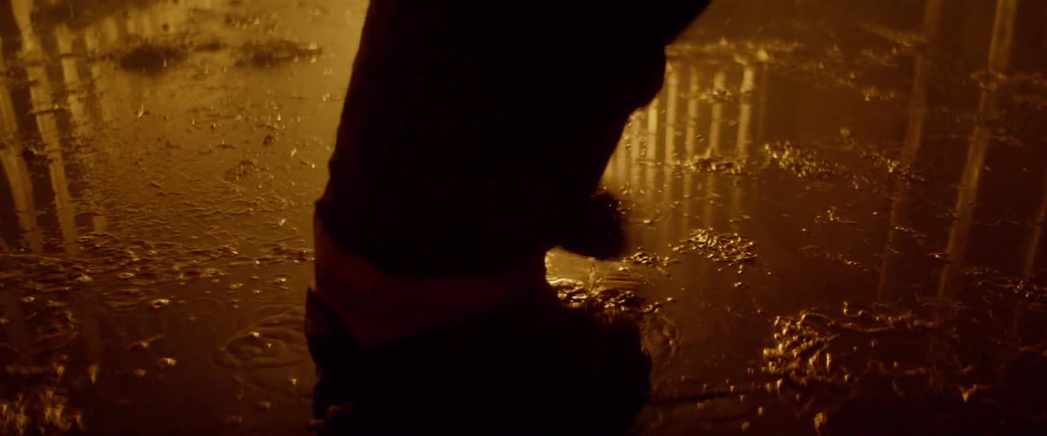 A firefighter runs through a puddle near a fire