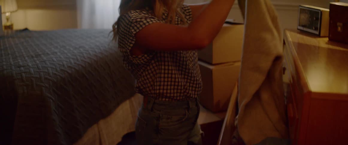 A woman is picking clothes from her dresser