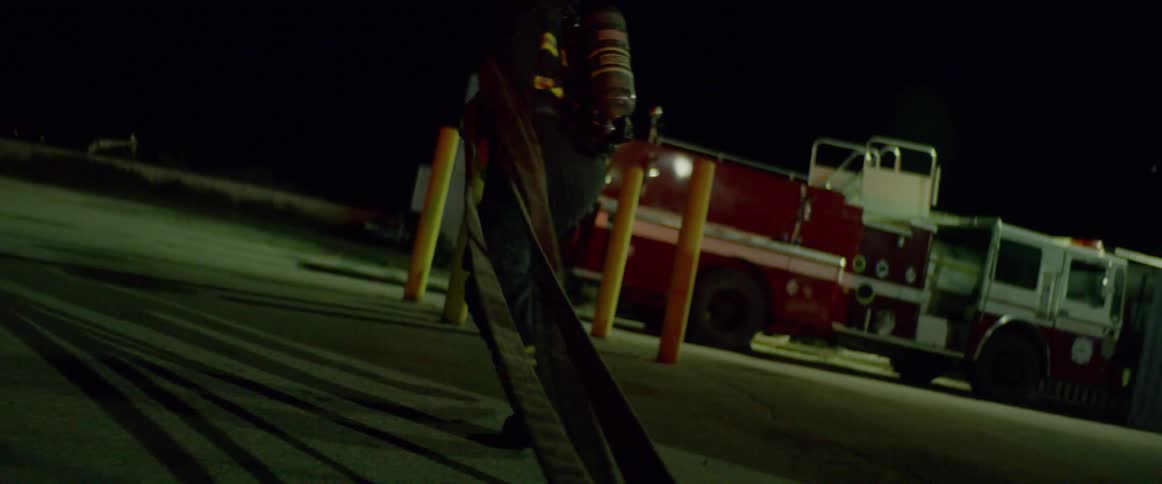 Firefighter runs and drags hose over the floor at night