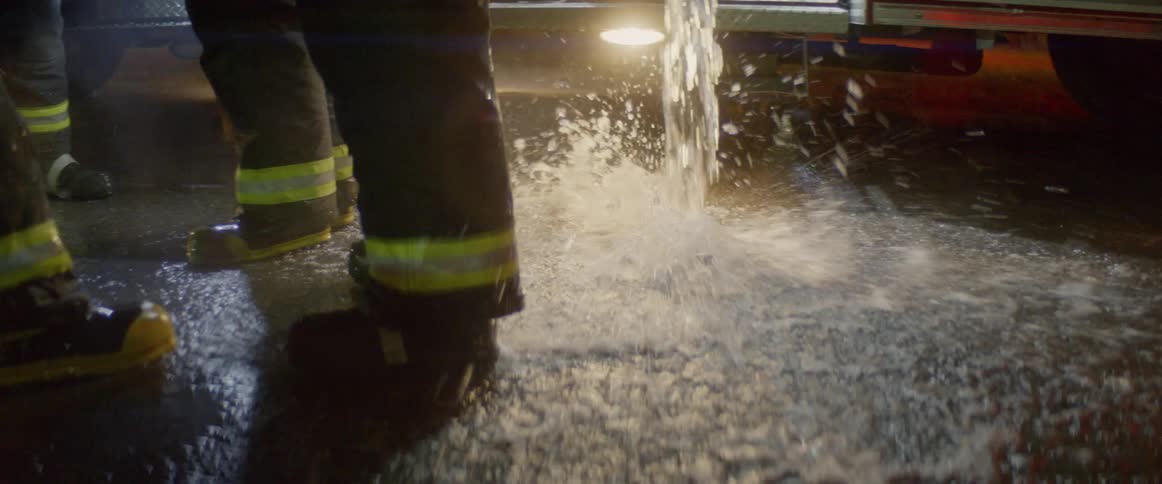 Firefighters watch as water empties from the truck