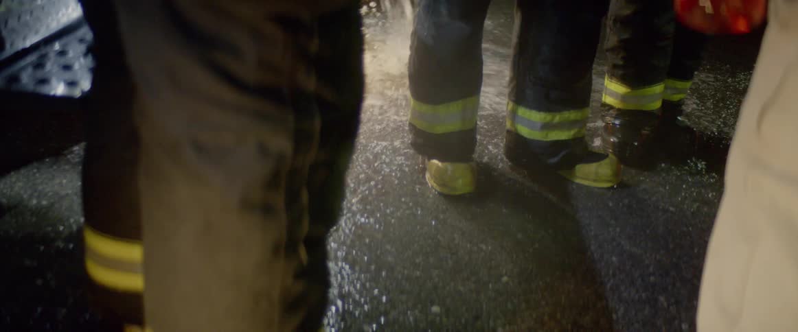 Water splashes and pools at the feet of firefighters