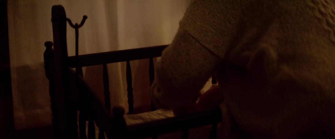 Mother places baby in crib near curtained window