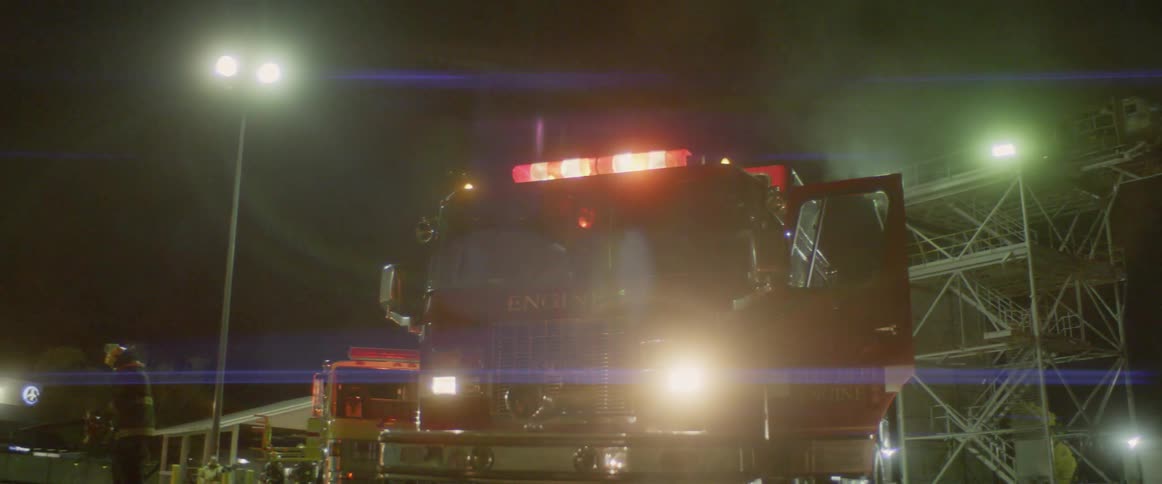 A parked fire truck flashing its sirens at night