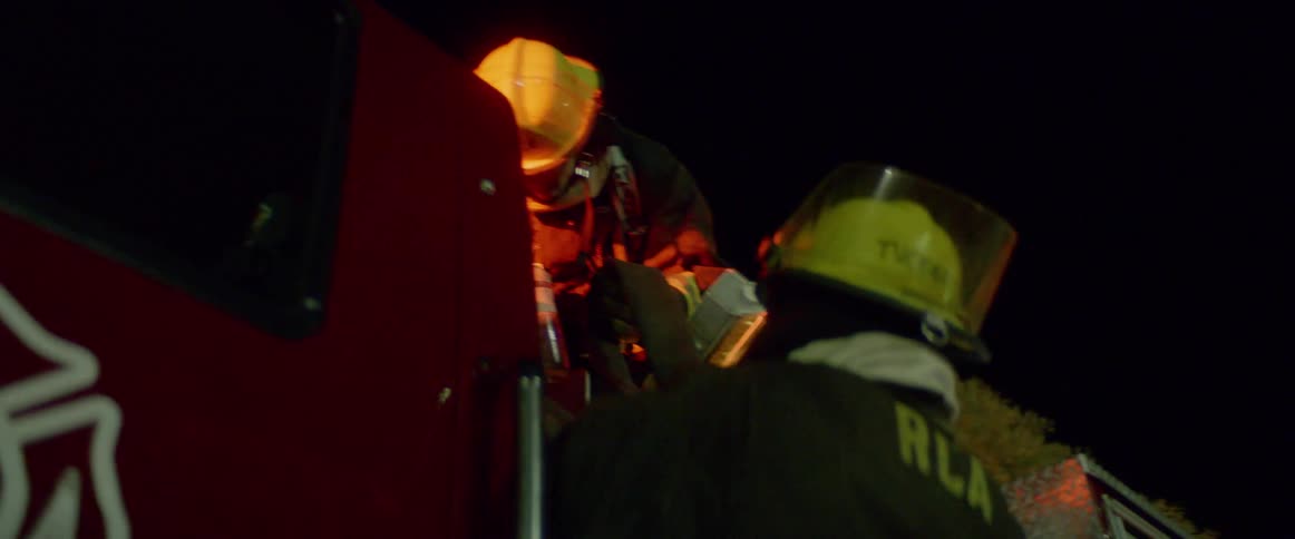 Firefighters looking at a hose on a fire truck