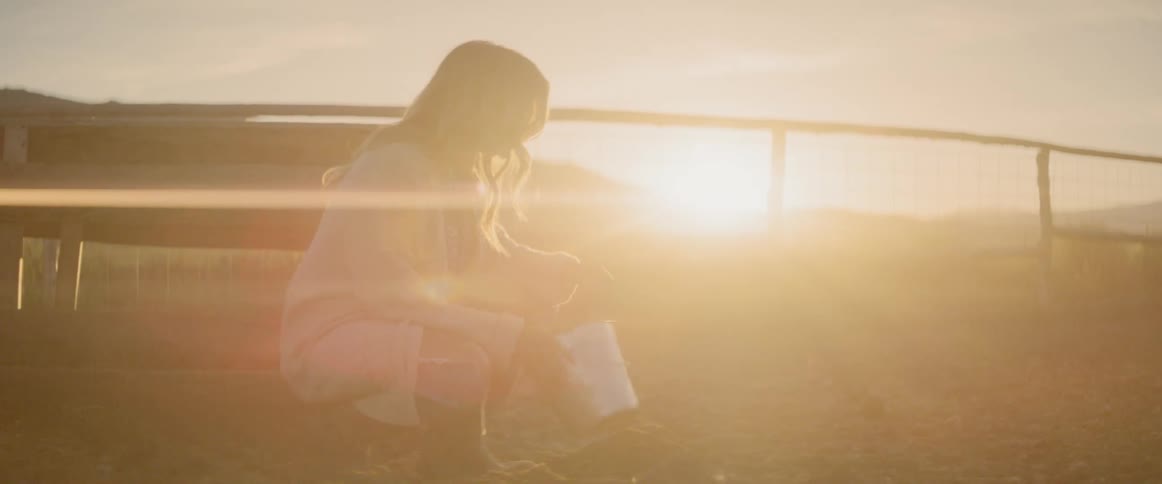 Girl plays with bucket in farm at sunset
