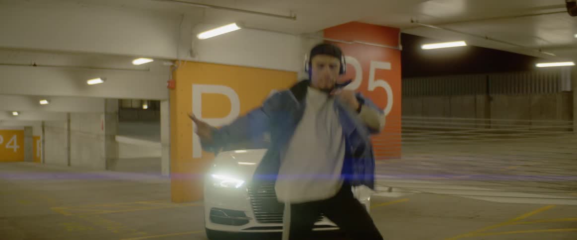 A young man dances in a parking garage