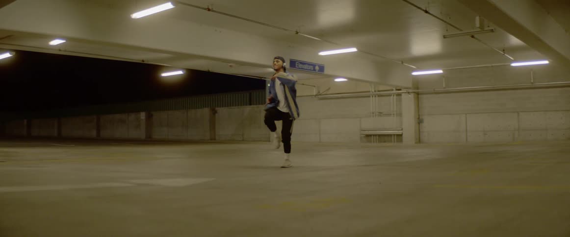 A teenager dances in a parking garage