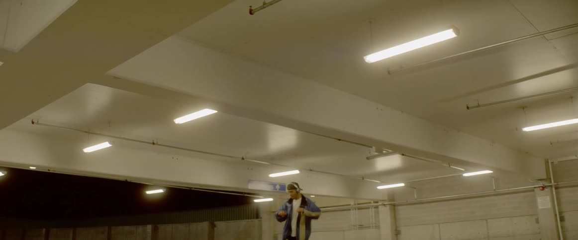 Man wearing headphones dances in a parking garage at night