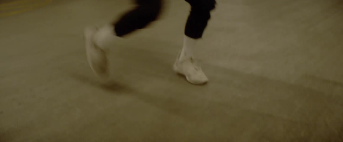 A man is dancing on concrete while wearing headphones