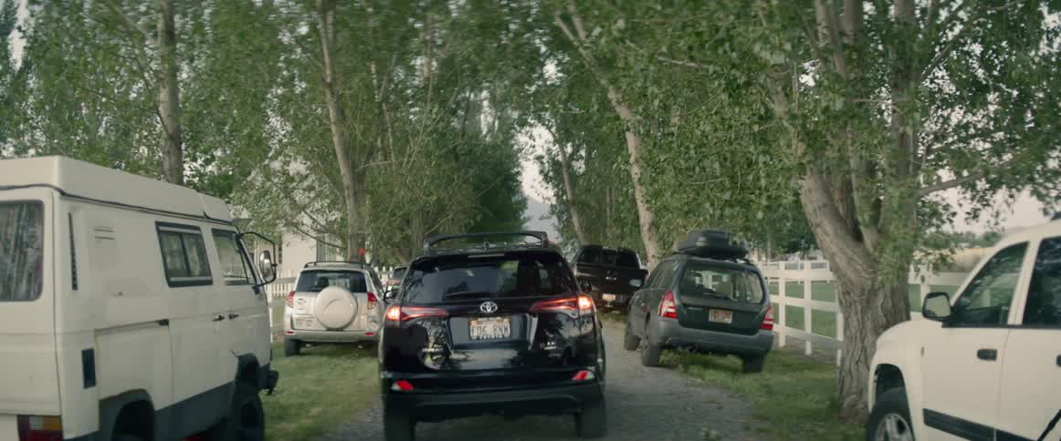 Vehicle driving between parked cars down rural road
