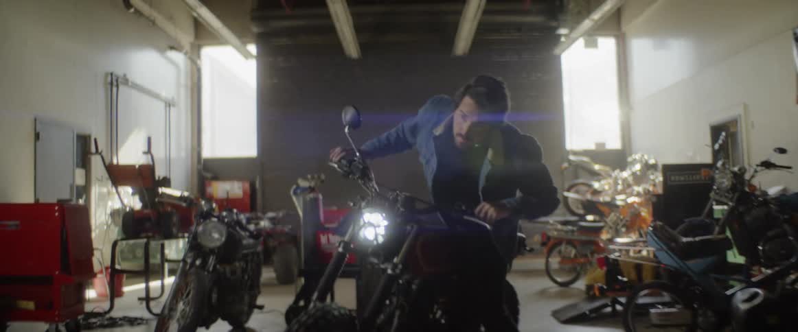 A man climbs on a motorcycle inside a large garage