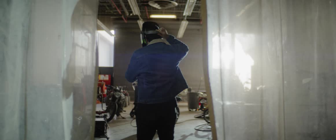 A person putting on a helmet while walking through a motorcycle garage
