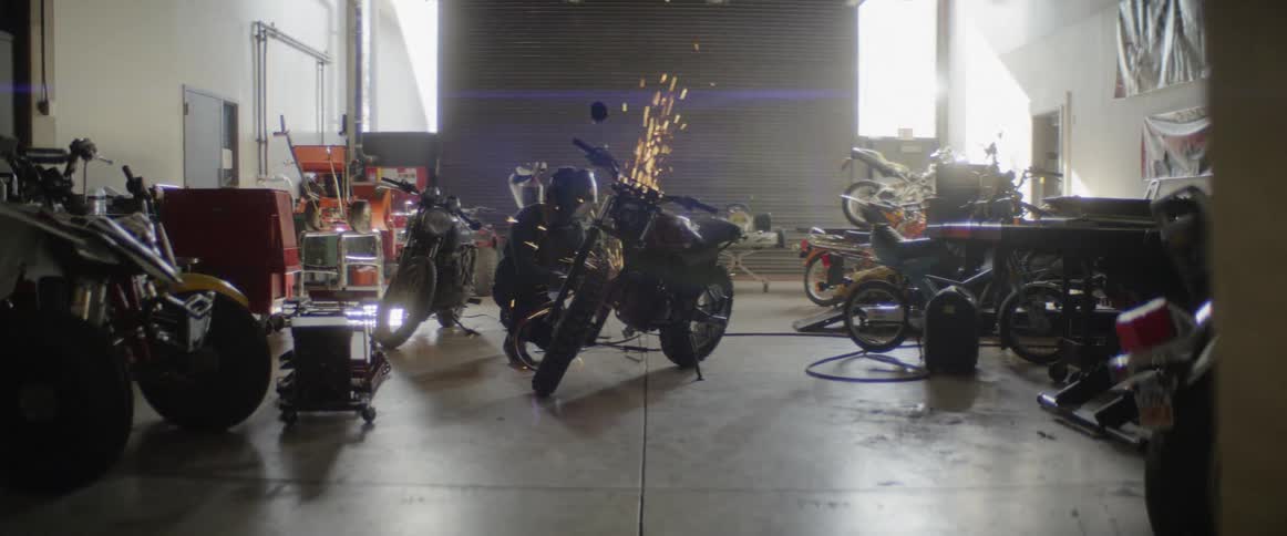 Worker cuts motorcycle part with grinder in a motorcycle repair shop