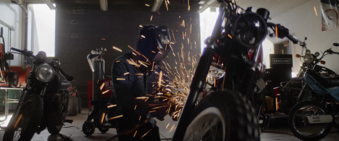 A man is working on motorcycles in a work shop